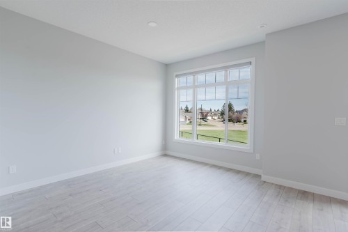 Bright interior space featuring a large multi-pane window with white trim - 3 11373 12 Avenue, Edmonton, AB - Indoor Photo Showing Other Room