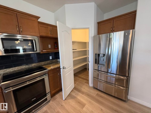 Built-in pantry shelving featuring white painted wood, corner configuration, multiple tiers, and wood-finish flooring - 2335 Rutherford Way, Edmonton, AB - Indoor With Storage