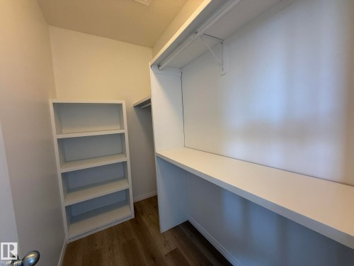 Walk-in closet featuring built-in shelving, a full-width countertop, and a clothes hanging rod - 2335 Rutherford Way, Edmonton, AB - Indoor