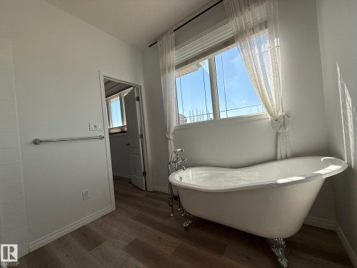 Freestanding clawfoot bathtub with chrome hardware, set against a window with sheer curtains - 2335 Rutherford Way, Edmonton, AB - Indoor Photo Showing Bathroom