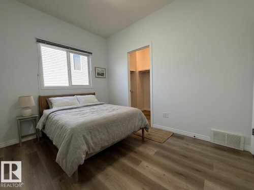Neutral interior space featuring wood-finish flooring, white baseboards, and a window with blinds - 2335 Rutherford Way, Edmonton, AB - Indoor Photo Showing Other Room