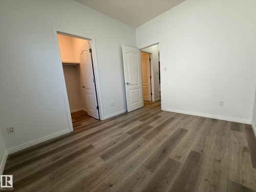 Spacious room featuring wood-finish flooring, crisp white walls, and a walk-in closet with built-in shelving - 2335 Rutherford Way, Edmonton, AB - Indoor Photo Showing Other Room