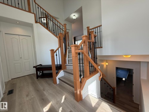 Staircase featuring wood railings with black iron spindles, light wood-finish flooring, and white walls - 2335 Rutherford Way, Edmonton, AB - Indoor Photo Showing Other Room