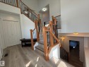 Staircase featuring wood railings with black iron spindles, light wood-finish flooring, and white walls - 2335 Rutherford Way, Edmonton, AB  - Indoor Photo Showing Other Room 