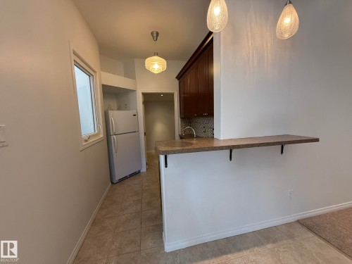 Kitchenette featuring a stainless steel refrigerator, white cabinetry, and a window for natural light - 2335 Rutherford Way, Edmonton, AB - Indoor Photo Showing Kitchen