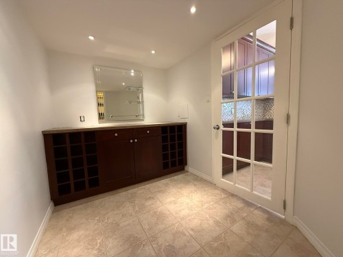 Custom built-in cabinetry with integrated wine storage, a stone countertop, and an overhead decorative mirror - 2335 Rutherford Way, Edmonton, AB - Indoor