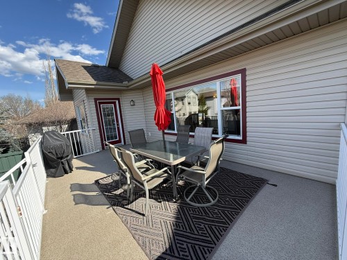 Spacious outdoor deck featuring light-colored speckled flooring, white railings, and siding - 2335 Rutherford Way, Edmonton, AB - Outdoor With Deck Patio Veranda With Exterior