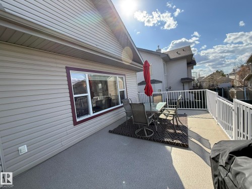 Spacious outdoor deck featuring a textured surface, white railing, and an adjacent window with deep red trim - 2335 Rutherford Way, Edmonton, AB - Outdoor With Deck Patio Veranda With Exterior
