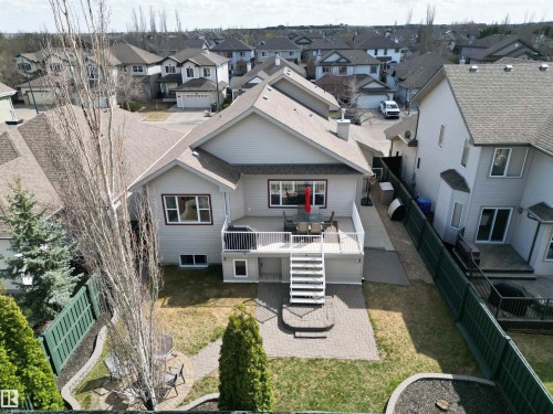 Rear exterior featuring a spacious deck with white railings and stairs descending to a paver patio - 2335 Rutherford Way, Edmonton, AB - Outdoor
