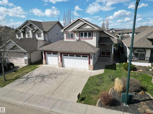 Two-story residence featuring light-colored siding with red trim accents, a multi-gabled roofline, and a double-wide driveway - 2335 Rutherford Way, Edmonton, AB - Outdoor With Facade