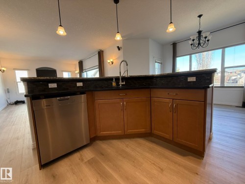 Kitchen featuring wood cabinetry, stainless steel appliances, granite countertops, and a black tile backsplash - 2335 Rutherford Way, Edmonton, AB - Indoor Photo Showing Kitchen