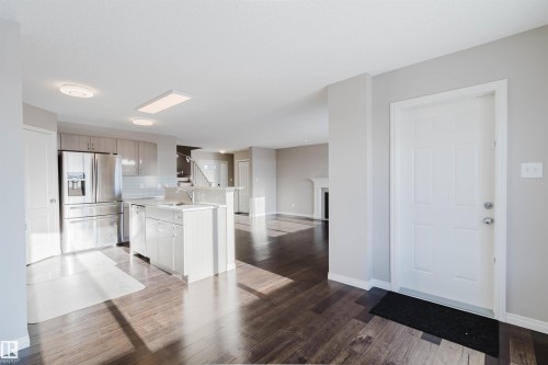 Open-concept living space featuring wood-finish flooring, a contemporary kitchen with stainless steel appliances, light cabinetry, and a subway tile backsplash - 16627 18 Avenue, Edmonton, AB - Indoor Photo Showing Kitchen