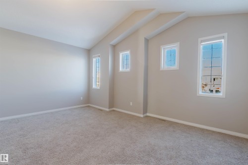 Spacious room featuring vaulted ceilings, light neutral wall tones, plush carpet flooring, and multiple window openings - 16627 18 Avenue, Edmonton, AB - Indoor Photo Showing Other Room