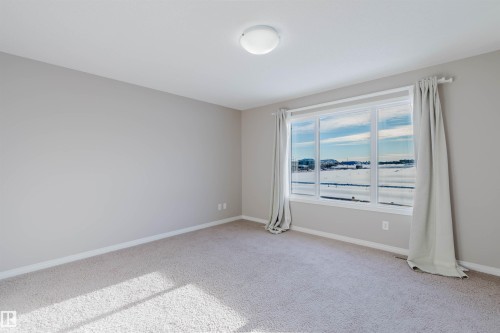 Bright room featuring a large multi-pane window, neutral-toned walls, light carpeting, and a flush-mount ceiling light - 16627 18 Avenue, Edmonton, AB - Indoor Photo Showing Other Room