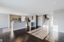 Spacious open-concept area featuring rich wood-finish flooring, a kitchen with light wood-finish cabinetry, stainless steel appliances, and a breakfast bar - 16627 18 Avenue, Edmonton, AB  - Indoor Photo Showing Kitchen 
