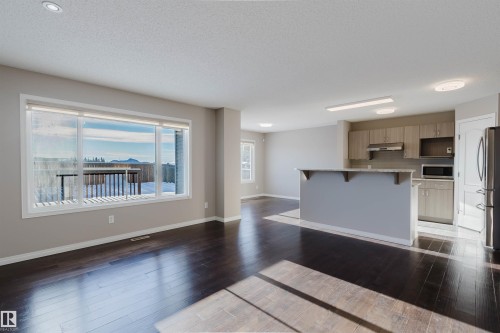 Spacious living area featuring dark wood-finish flooring, a large picture window, and recessed lighting - 16627 18 Avenue, Edmonton, AB - Indoor