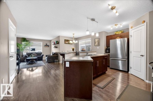 Open-concept kitchen featuring dark wood cabinetry, light countertops, and a stainless steel refrigerator - 18080 89 Street, Edmonton, AB - Indoor Photo Showing Kitchen With Double Sink