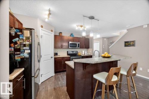 Kitchen featuring wood-finish flooring, dark wood cabinetry, and a light-toned countertop - 18080 89 Street, Edmonton, AB - Indoor Photo Showing Kitchen