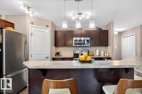 Kitchen featuring an eat-at island, dark wood-finish cabinetry, stainless steel appliances, a tiled backsplash, and recessed lighting - 18080 89 Street, Edmonton, AB - Indoor Photo Showing Kitchen With Upgraded Kitchen