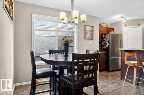Dining area featuring a contemporary chandelier, large window with blinds, and wood-finish flooring - 18080 89 Street, Edmonton, AB - Indoor Photo Showing Dining Room