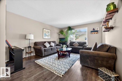 Living area featuring wood-finish flooring, neutral wall tones, and a large window providing natural illumination - 18080 89 Street, Edmonton, AB - Indoor Photo Showing Living Room