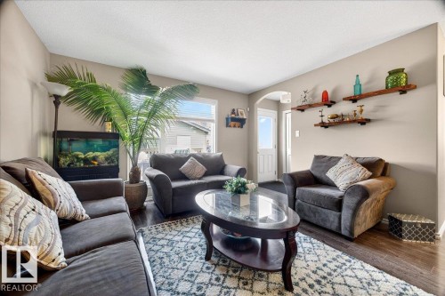 Spacious living area featuring wood-finish flooring, neutral wall tones, and arched doorway - 18080 89 Street, Edmonton, AB - Indoor Photo Showing Living Room With Fireplace