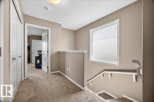 Upper-level landing featuring textured carpeting, neutral wall finishes, and a window with blinds - 18080 89 Street, Edmonton, AB - Indoor