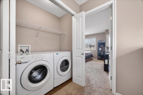 Dedicated laundry area featuring front-loading appliances, overhead wire shelving, and neutral wall tones - 18080 89 Street, Edmonton, AB - Indoor Photo Showing Laundry Room