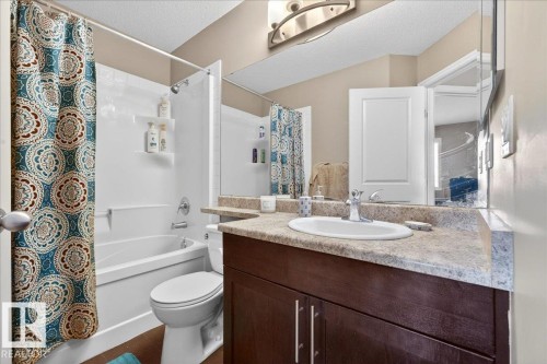 Bathroom featuring a tub/shower combination with white surround, a toilet, a vanity with a laminate countertop, and an integrated sink with a chrome faucet - 18080 89 Street, Edmonton, AB - Indoor Photo Showing Bathroom