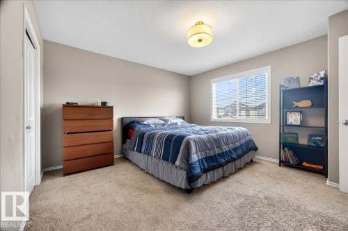 Bedroom featuring neutral wall paint, textured carpeting, a large window with blinds, and a ceiling-mounted light fixture - 18080 89 Street, Edmonton, AB - Indoor Photo Showing Bedroom