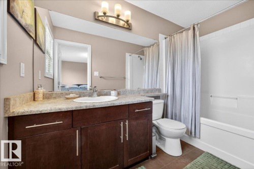 Bathroom featuring a dark wood-finish vanity with a light-toned countertop, an undermount sink, and a large wall-mounted mirror - 18080 89 Street, Edmonton, AB - Indoor Photo Showing Bathroom