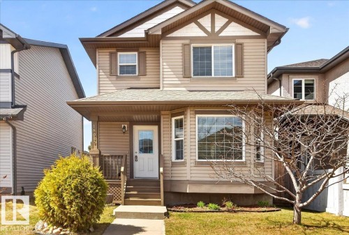 Two-story residence featuring light brown horizontal siding, a covered front porch with white railing, and a bay window - 18080 89 Street, Edmonton, AB - Outdoor