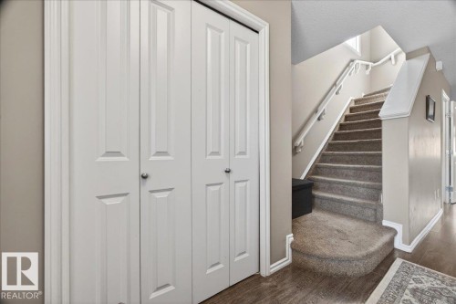 Entryway featuring white bi-fold closet doors, wood-finish flooring, and a carpeted staircase with white handrails - 18080 89 Street, Edmonton, AB - Indoor Photo Showing Other Room