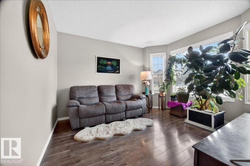 Living area featuring wood-finish flooring, bay windows, and light gray wall paint - 18080 89 Street, Edmonton, AB - Indoor Photo Showing Living Room