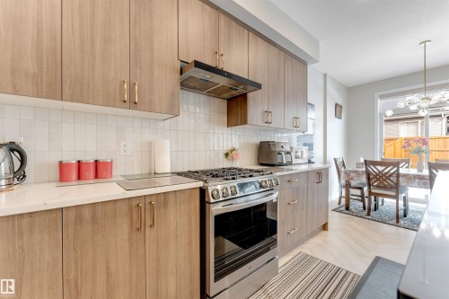 Modern kitchen with wood-finish cabinetry, white subway tile backsplash, and stainless steel gas range - 6404 27 Avenue, Edmonton, AB - Indoor Photo Showing Kitchen With Upgraded Kitchen