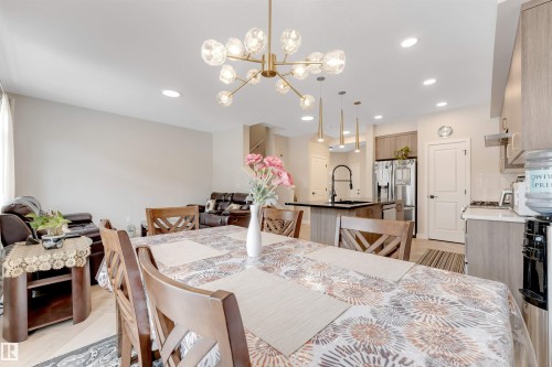 Open-concept dining area featuring a contemporary chandelier and wood-finish flooring - 6404 27 Avenue, Edmonton, AB - Indoor Photo Showing Dining Room