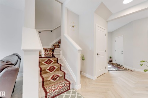 Two-story entry foyer featuring light-toned flooring, white trim, and a staircase with a patterned runner - 6404 27 Avenue, Edmonton, AB - Indoor Photo Showing Other Room