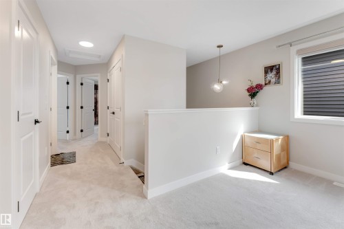 Carpeted hallway with multiple white panel doors featuring matte black hardware - 6404 27 Avenue, Edmonton, AB - Indoor Photo Showing Other Room