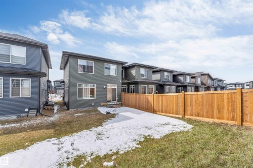 Rear exterior featuring a sliding glass door, multiple windows, a private wooden fence, and a partially grassed yard - 6404 27 Avenue, Edmonton, AB - Outdoor