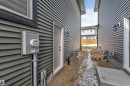 Exterior utility access featuring a window with dark trim, dark grey horizontal siding, and an exterior door - 6404 27 Avenue, Edmonton, AB  - Outdoor With Exterior 