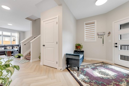 Entryway featuring wood-finish herringbone flooring, a modern panel-style front door with horizontal lites, and a white interior door - 6404 27 Avenue, Edmonton, AB - Indoor Photo Showing Other Room