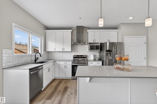 Modern kitchen featuring white cabinetry, stainless steel appliances, light-toned countertops, subway tile backsplash, and wood-finish flooring - 22638 99A Avenue, Edmonton, AB - Indoor Photo Showing Kitchen With Upgraded Kitchen