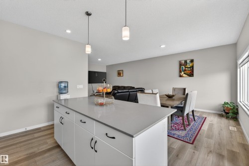 Kitchen island featuring a light gray countertop, white cabinetry with black hardware, and two pendant lights - 22638 99A Avenue, Edmonton, AB - Indoor