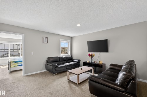 Carpeted living area featuring light gray walls, recessed lighting, and a window with exterior residential structures visible - 22638 99A Avenue, Edmonton, AB - Indoor Photo Showing Living Room