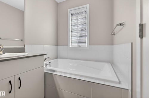 White drop-in bathtub with chrome fixtures, surrounded by white subway tile wainscoting - 22638 99A Avenue, Edmonton, AB - Indoor Photo Showing Bathroom