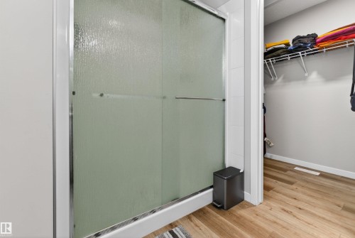 Frosted glass shower enclosure with chrome hardware, white tile surround, and wood-finish flooring - 22638 99A Avenue, Edmonton, AB - Indoor