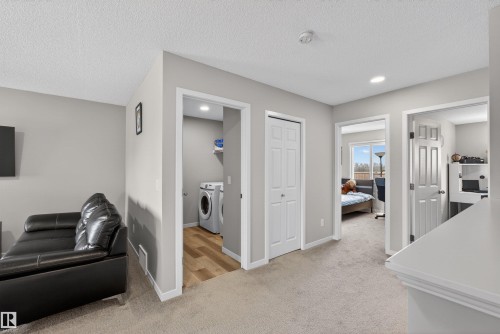 Upper-level landing featuring neutral carpeting, a laundry area with wood-finish flooring, and multiple doorways leading to additional rooms - 22638 99A Avenue, Edmonton, AB - Indoor