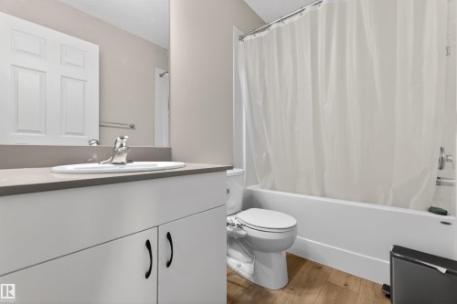 Bathroom featuring a white vanity with a gray countertop, an undermount sink with chrome fixtures, wood-finish flooring, and a shower-tub combination - 22638 99A Avenue, Edmonton, AB - Indoor Photo Showing Bathroom