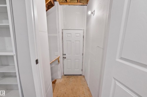 Entryway featuring a white paneled door with dark hardware, a wall-mounted light fixture, and visible wood flooring - 22638 99A Avenue, Edmonton, AB - Indoor Photo Showing Other Room
