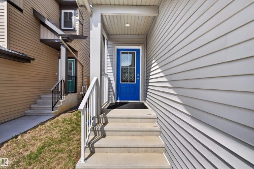 Entryway featuring a vibrant blue door with decorative glass, concrete steps, white railings, and horizontal siding - 22638 99A Avenue, Edmonton, AB - Outdoor With Exterior